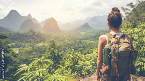 Back view of a woman with a backpack overlooking misty mountains