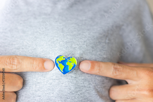 Earth Day: heart-shaped Earth pin proudly worn on a person\'s chest, emphasizing love for our planet and the call to preserve it