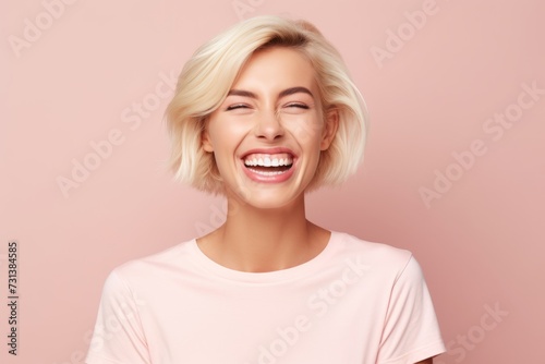 Cheerful young woman with blonde hair. Studio shot on pink background.