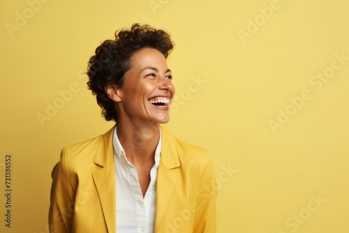 happy african american woman in yellow jacket laughing on yellow background © Inigo