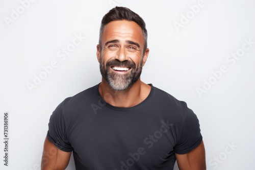 Portrait of a handsome middle-aged man smiling while standing against grey background