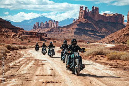 group of bikers riding through a mountain pass at sunset. The riders are wearing helmets and leather jackets, and there are snow-capped peaks in the background