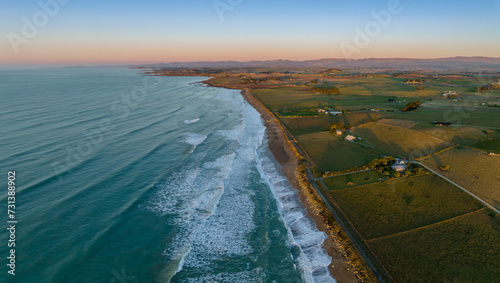 Aerial: Ocean beach and farmalnd at sunrise. Oamaru, Otago, New Zealand.