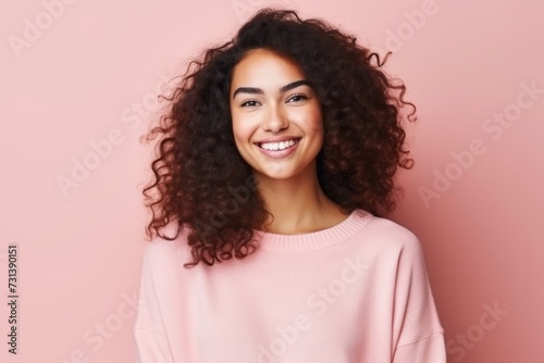 Portrait of a beautiful young african american woman smiling over pink background © Inigo