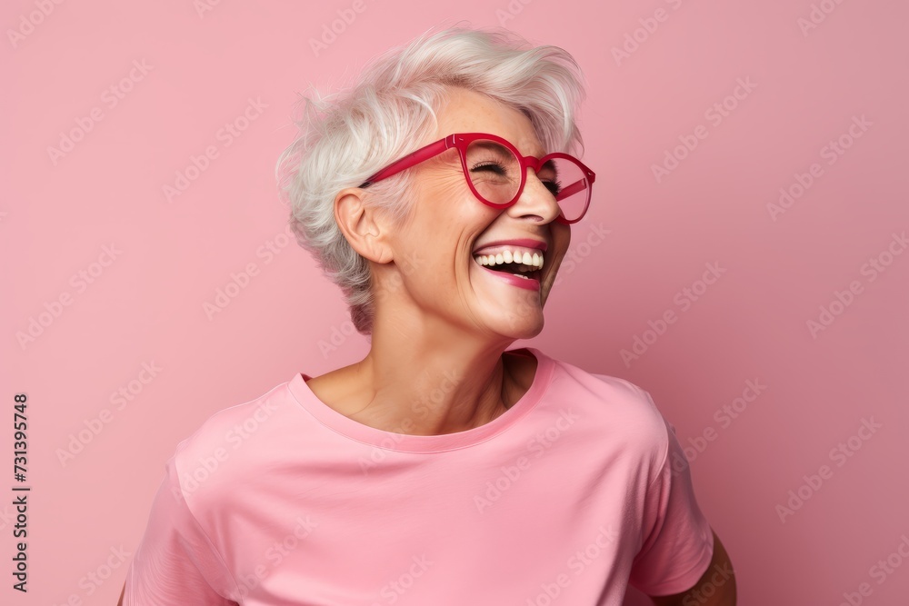 Portrait of a happy senior woman in red glasses on a pink background