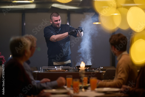 In a restaurant setting, a professional chef presents a sizzling steak cooked over an open flame, while an European Muslim family eagerly awaits their iftar meal during the holy month of Ramadan