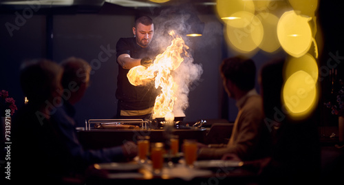 In a restaurant setting, a professional chef presents a sizzling steak cooked over an open flame, while an European Muslim family eagerly awaits their iftar meal during the holy month of Ramadan