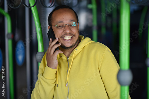 a lustful dark-skinned young man is sitting in the bus and talking on the phone