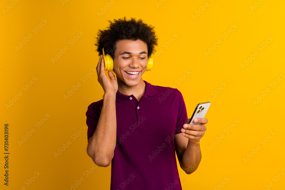 Photo of funky positive man wear stylish clothes listen audio playlist read social media on iphone isolated over yellow color background Photo of funky positive man wear stylish clothes listen audio playlist read social media on iphone isolated over yellow color background