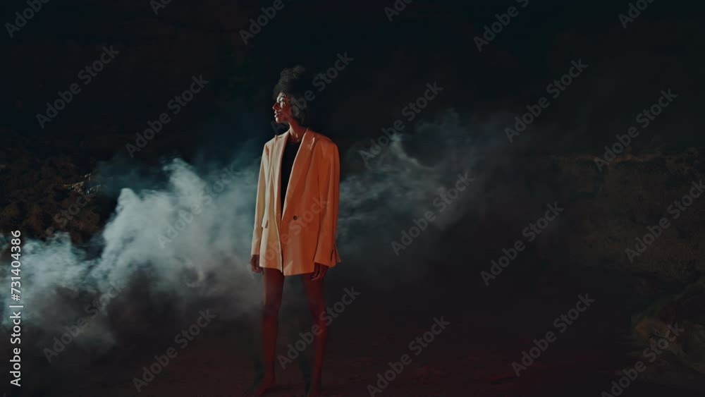 Trendy lady modeling smoke fog on beach. Attractive slim woman looking camera Trendy lady modeling smoke fog on beach. Attractive slim woman looking camera