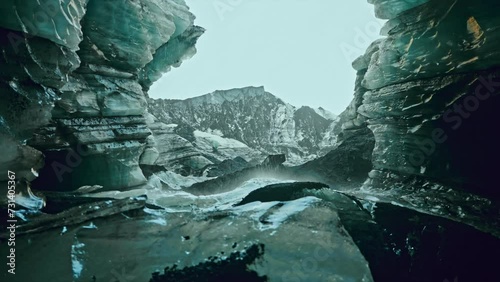 Cinematic shot inside the Katla ice caves, near Vik, southern Iceland.
View of the frozen subglacial landscape. Water falling down the caves walls. photo