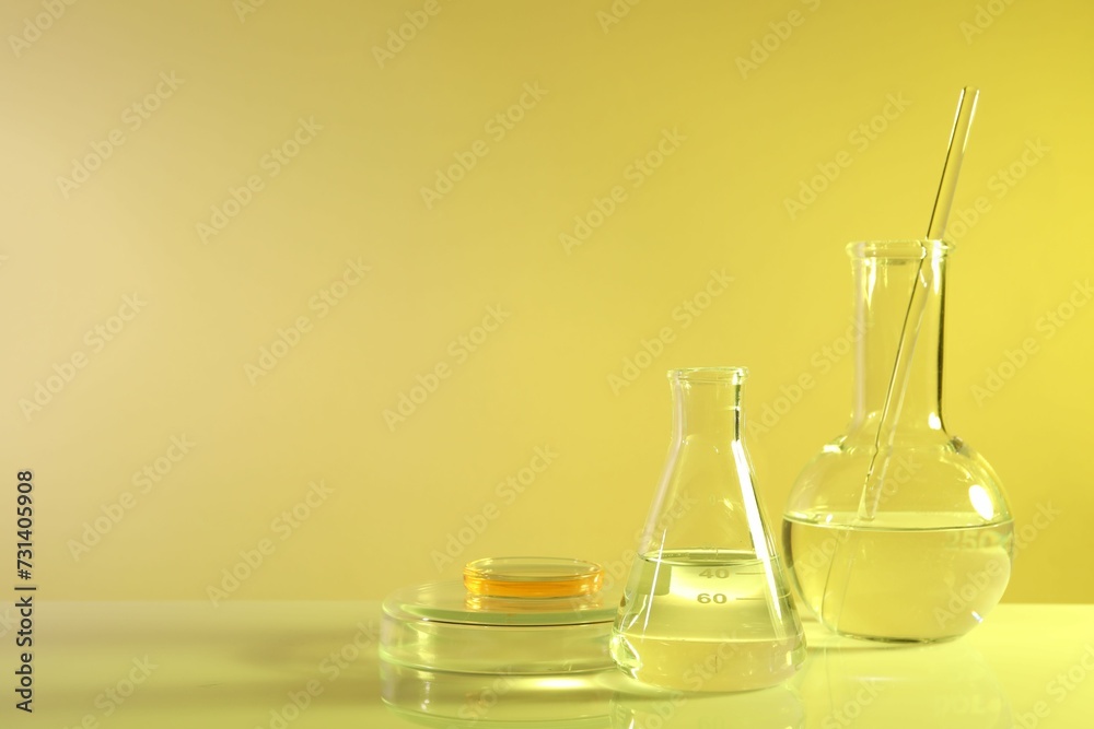 Laboratory analysis. Different glassware on table against yellow background, space for text