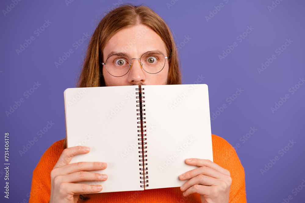 Close up photo of funny nerd student guy shocked realizing read his planner forgot about exam tomorrow isolated on violet color background Close up photo of funny nerd student guy shocked realizing read his planner forgot about exam tomorrow isolated on violet color background