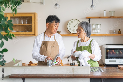 お皿洗い・食器洗いの家事をするアジア人の高齢者夫婦 