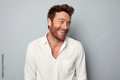 Portrait of a happy young man laughing against a grey background. © Inigo