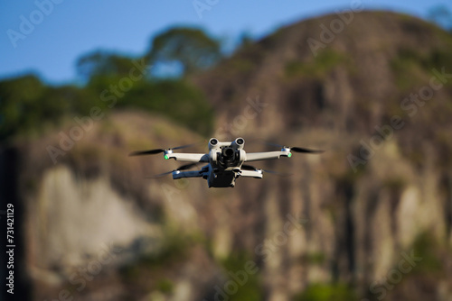 A small sized drone flying with rocky mountain backgrounds. Mini remote control aircraft on flight in outdoor area. Concept for travel ultralight drone. photo