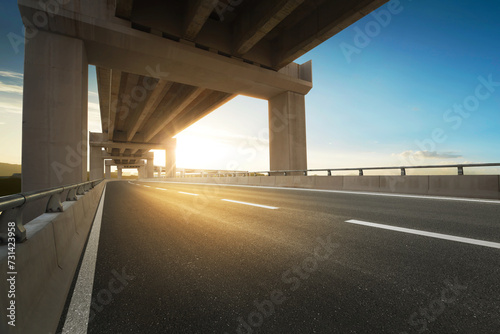 Modern highway road under the overpass with sunset sky.