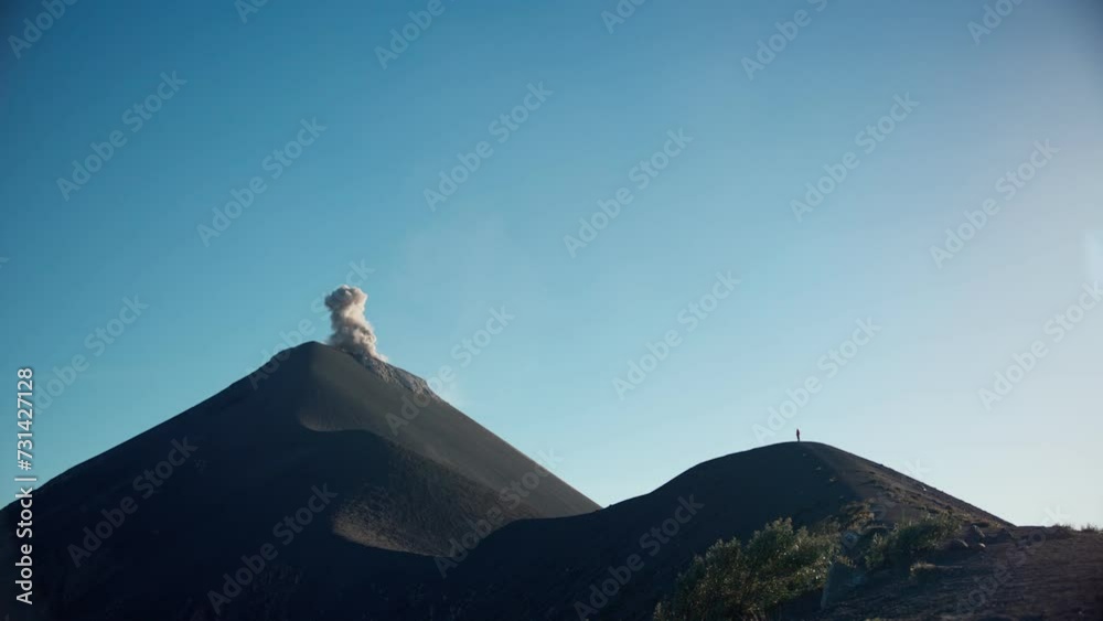 Single person standing on ridge of erupting Fuego Volcano. Runs toward exploding ash cloud. Late afternoon shot