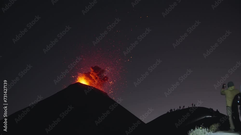 Massive Fuego volcano eruption at night with onlookers capturing explosive glowing lava and ash spectacle Massive Fuego volcano eruption at night with onlookers capturing explosive glowing lava and ash spectacle