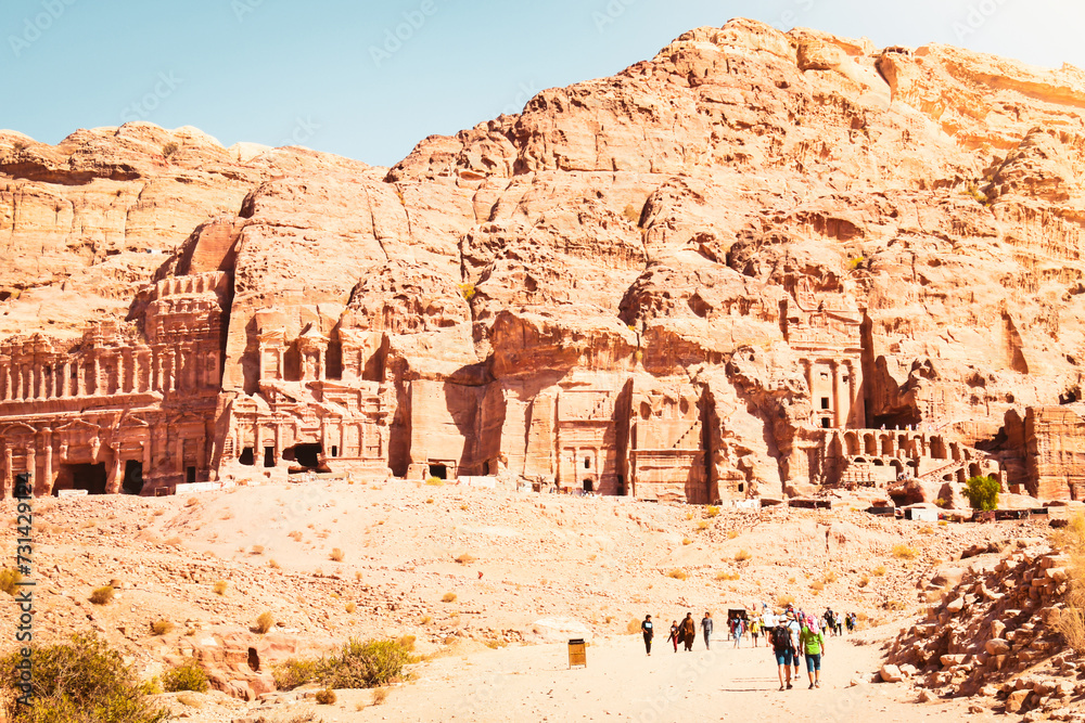 Tourists walk visit Petra historical landmark in Jordan on summer with scenic panorama of sacred tombs