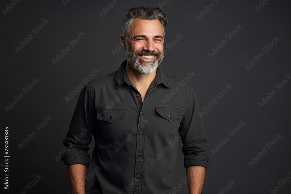 Portrait of a handsome mature man with grey hair and beard smiling at the camera against a dark background Portrait of a handsome mature man with grey hair and beard smiling at the camera against a dark background