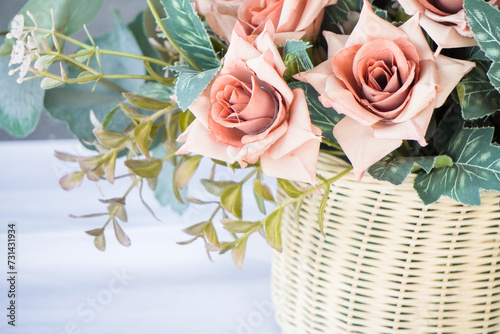 Modern interior design of modern dining room or office workplace with artificial plant. Plastic rose flower bouquet with woven rattan pots on the table with empty blank copy text place. photo