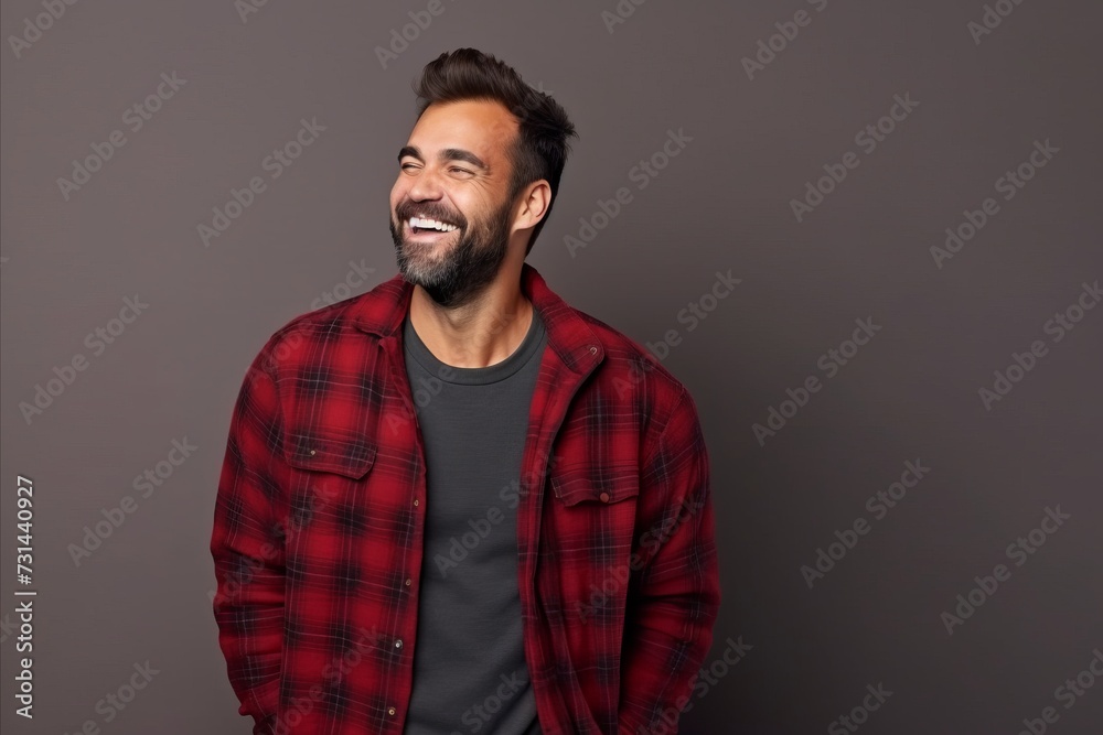 Portrait of a handsome young man smiling at the camera while standing against grey background Portrait of a handsome young man smiling at the camera while standing against grey background