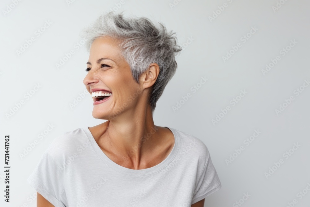 Closeup portrait of happy senior woman with grey hair laughing over gray background Closeup portrait of happy senior woman with grey hair laughing over gray background