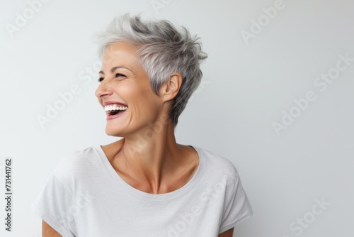 Closeup portrait of happy senior woman with grey hair laughing over gray background