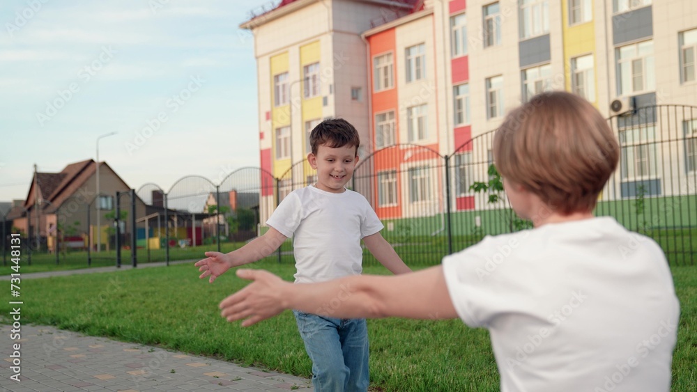 Child, son, runs to his mother hugs her on street. Happy family, Kid. Child has fun outside with his mother in summer. Carefree childhood, joyful embrace of child by mother. Family Mom, boy in park