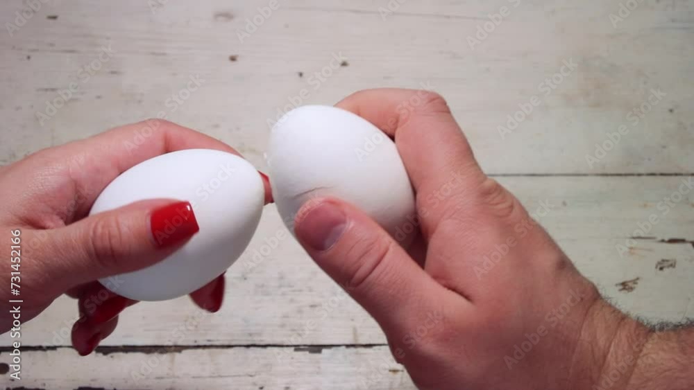 Full HD video. Russian traditional game. Happy Easter. Egg battle. White hen egg in male hand is broken against egg in female hand. Woman and man compete. Victory. Tradition. Broken eggshell