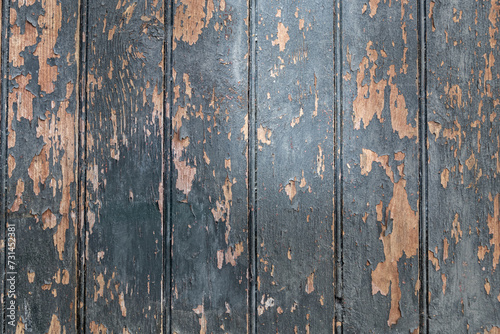 Old wooden boards painted with dark paint, which has partially peeled off due to time and weather conditions