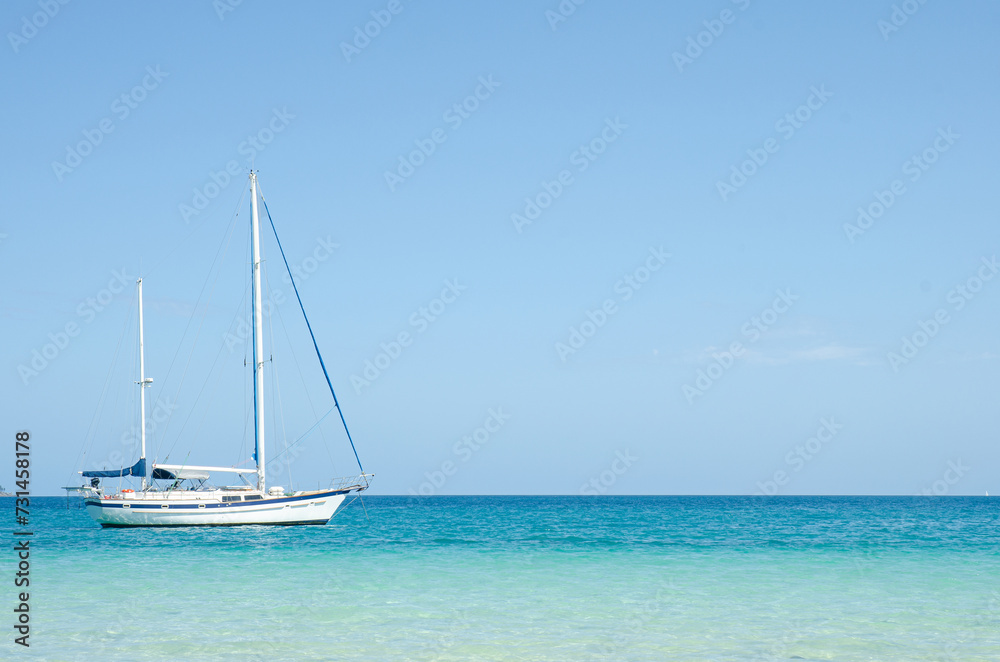 One white yacht with tall masts on blue water with clear blue sky. Australia. No people.