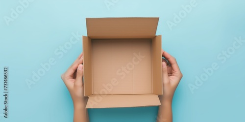 One empty open brown cardboard box on blue background. Top view © DailyStock