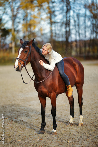 Young blonde girl with her brown horse on the riding arena in portraits. © RD-Fotografie