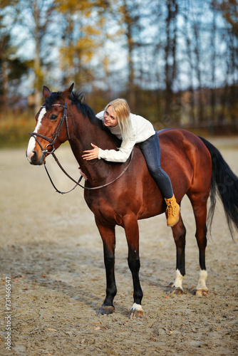 Young blonde girl with her brown horse on the riding arena in portraits. © RD-Fotografie