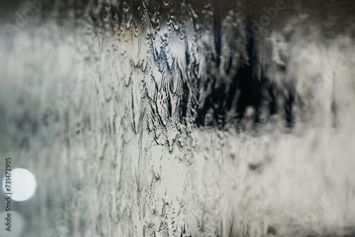 In a close-up capture, the texture of glass through which water flows is beautifully depicted, showcasing intricate patterns and the fluidity of movement in a mesmerizing display