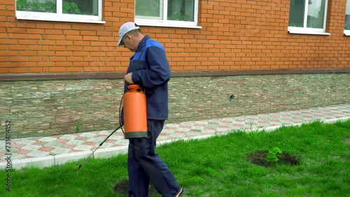 A man works in the garden, spraying weeds from a sprayer