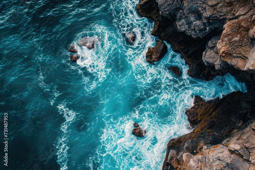 This breathtaking aerial shot captures the splendor of the ocean and rocks in one stunning display  A bird s eye view of turquoise sea waves crashing against enormous rocks  AI Generated