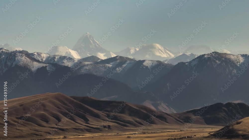 Mountainous terrain with beautiful skin rocky slopes with snow peaks background. Martian plateau landscape in Kazakhstan at summer sunny sunset.