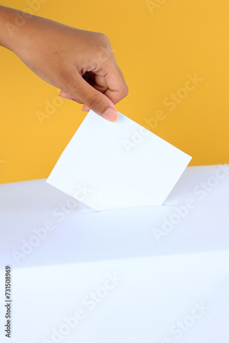 Female Hand Inserting Card Surat Suara to the Box Kotak. photo
