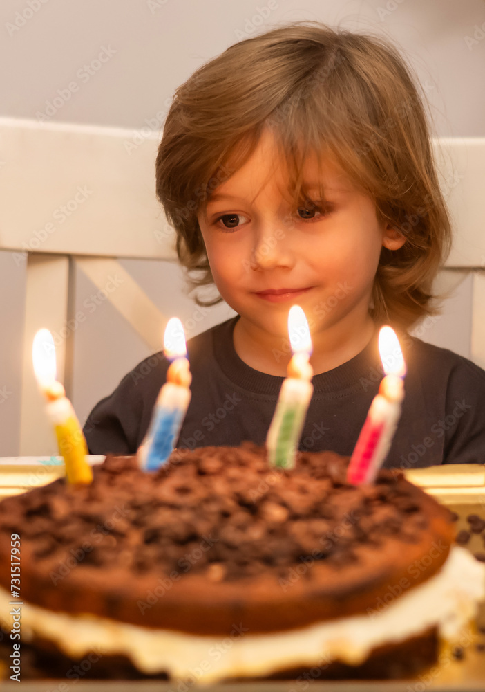Little Boy at His Birthday Party, He Is Excited Looking at the Cake with the Candles. Children's Birthday Parties Concept. Little Boy at His Birthday Party, He Is Excited Looking at the Cake with the Candles. Children's Birthday Parties Concept.