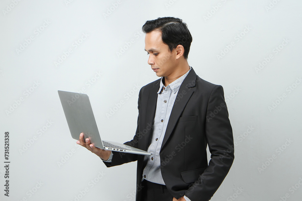 asian indonesian business man in suit holding laptop computer on isolated background asian indonesian business man in suit holding laptop computer on isolated background