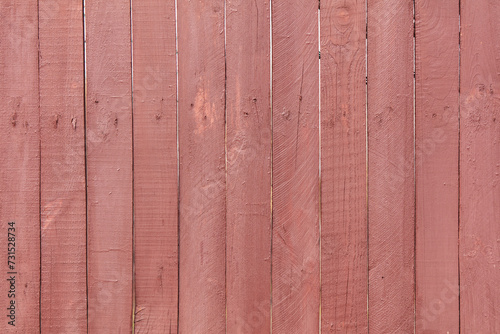 A wooden fence is painted with red paint as a background