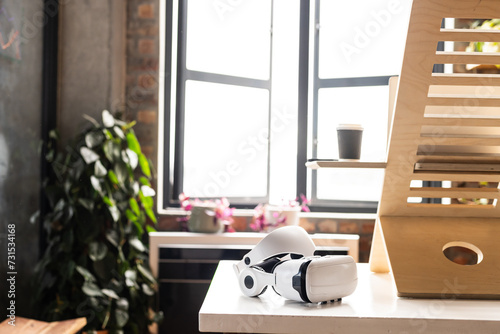 A VR headset rests on a modern desk at home, with copy space photo