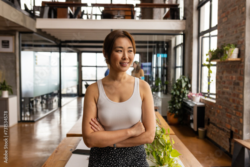 Confident Asian woman stands in a modern office, exuding casual business professionalism photo