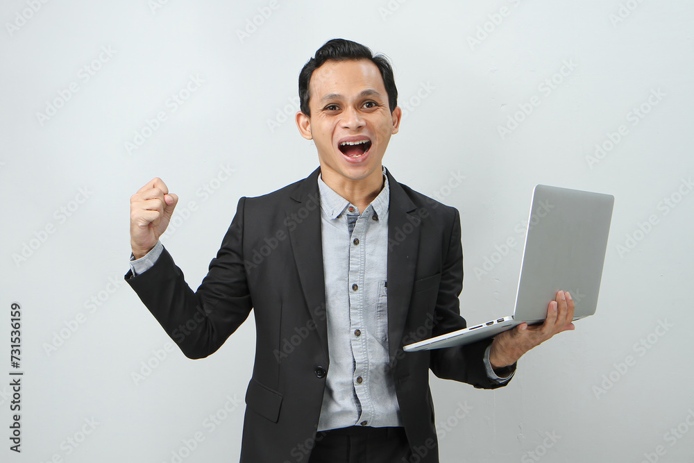 Happy asian indonesian business man in suit holding laptop computer on isolated background Happy asian indonesian business man in suit holding laptop computer on isolated background