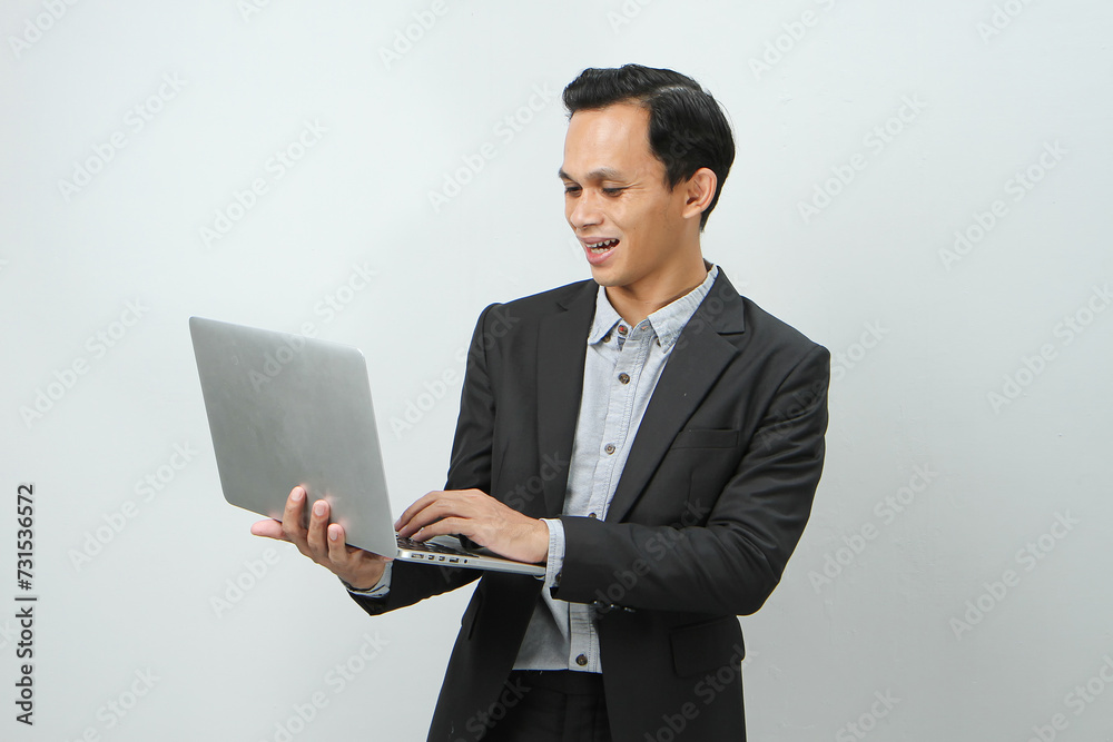 Happy asian indonesian business man in suit holding laptop computer on isolated background Happy asian indonesian business man in suit holding laptop computer on isolated background