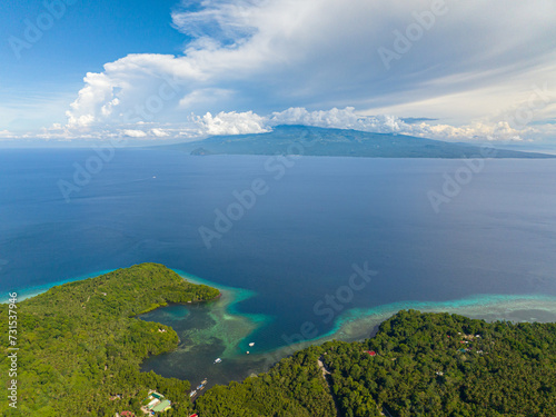 Tropical island with turquoise water at coast, blue sea under the blue sky and clouds. Camiguin Island, Philippines.