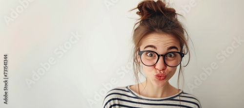 Portrait of stylish young woman wearing sunglasses and striped t-shirt on grey background. Portrait of beautiful young woman blowing her lips sending sweet air kiss